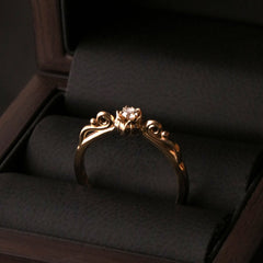 LILY OF LOVE 18K gold ring with diamond shown in a dark jewelry box beside the 2024 Ring of the Year badge