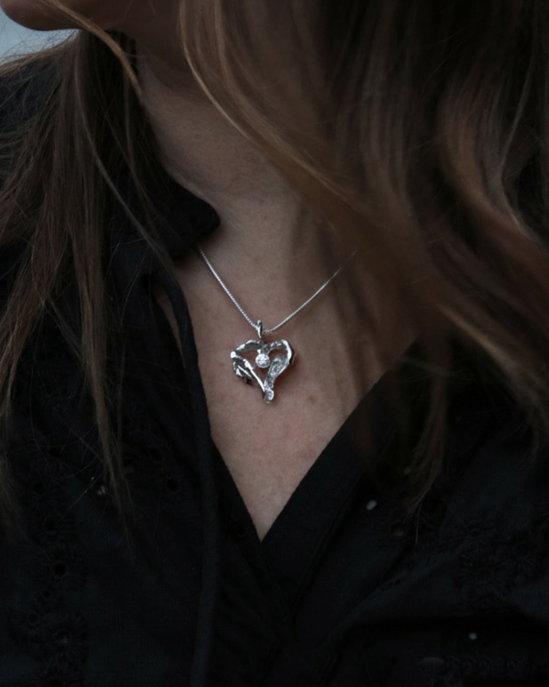 På modell syns ett silver halsband med ett hjärtformat hänge och kubisk zirkon.