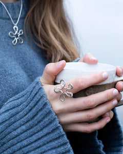 Model wearing BLOMMAN Elegant ring in silver with flower motif while holding a mug