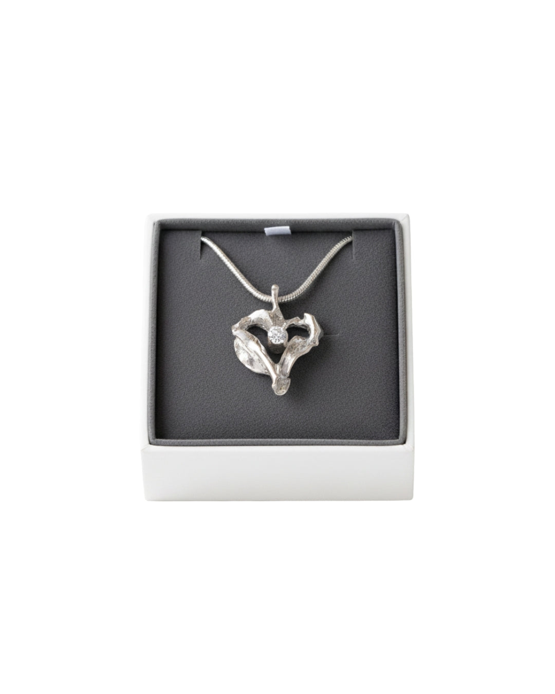 Två silver hjärtformade hängen i en presentbox, ena med klar kubisk zirkon och den andra utan sten.