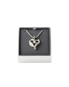 Två silver hjärtformade hängen i en presentbox, ena med klar kubisk zirkon och den andra utan sten.