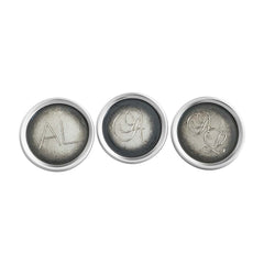 Three round sterling silver cufflinks with darkened centers and engraved initials inspired by old typewriters.