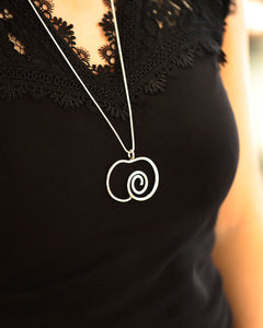 Argentum Delicata XL halsband i 925 sterlingsilver med ett äppleformigt spiralhänge mot en svart spetsklänning