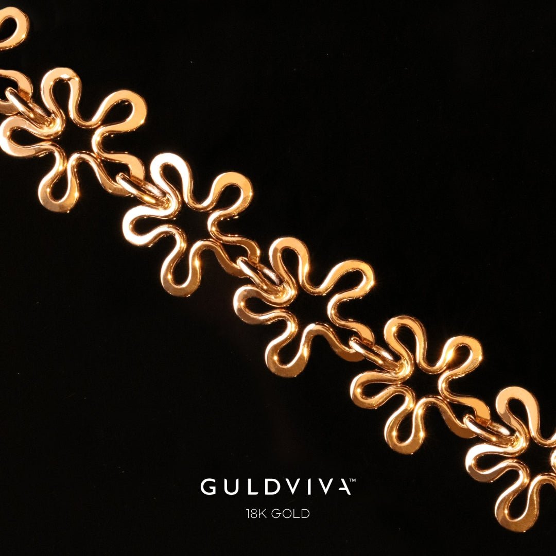 Detaljbild av BLOMMAN armband i 18K guld med blomformade länkar mot svart bakgrund