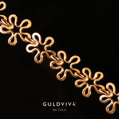 Detaljbild av BLOMMAN armband i 18K guld med blomformade länkar mot svart bakgrund