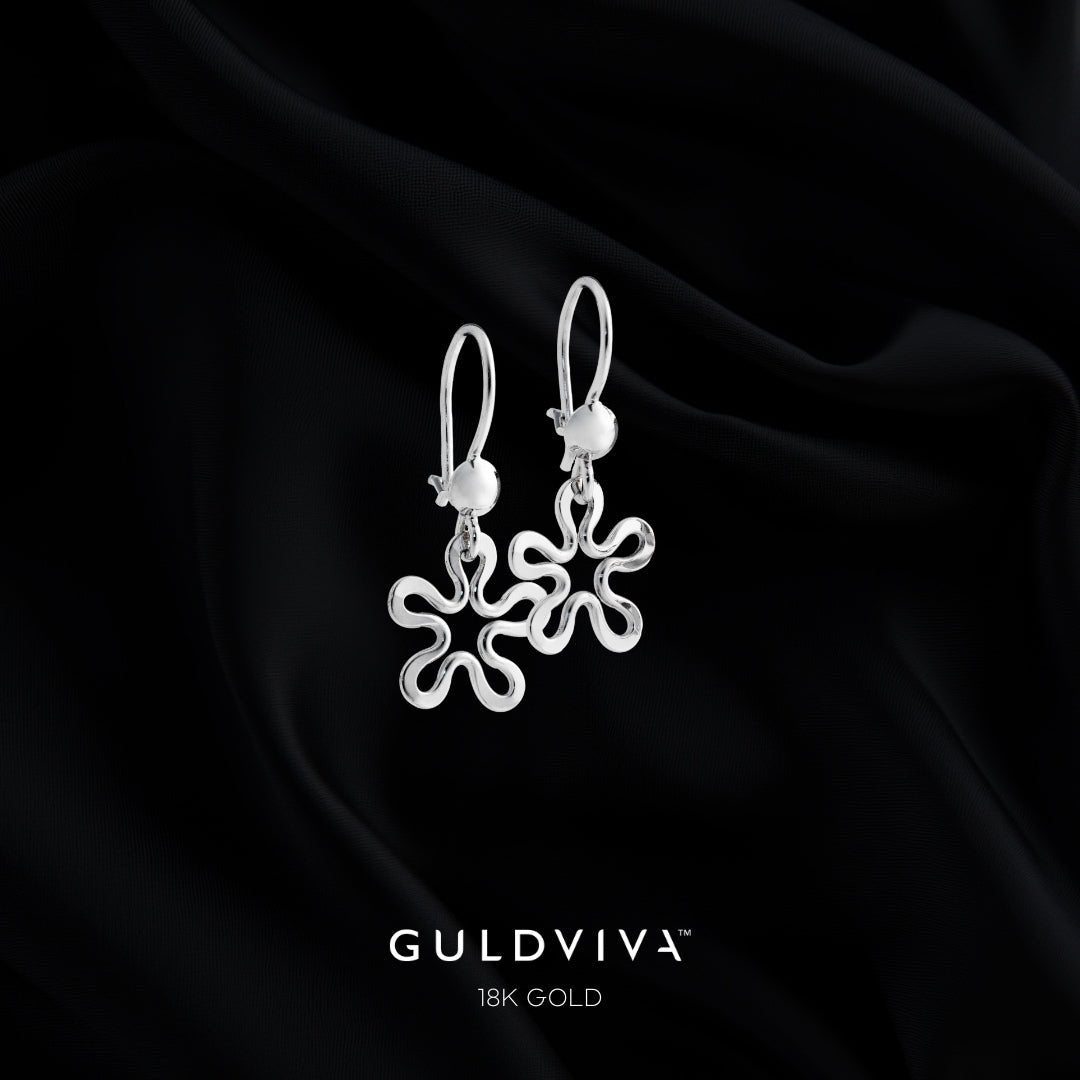 Blomman 18K white gold flower earrings on hooks against black fabric