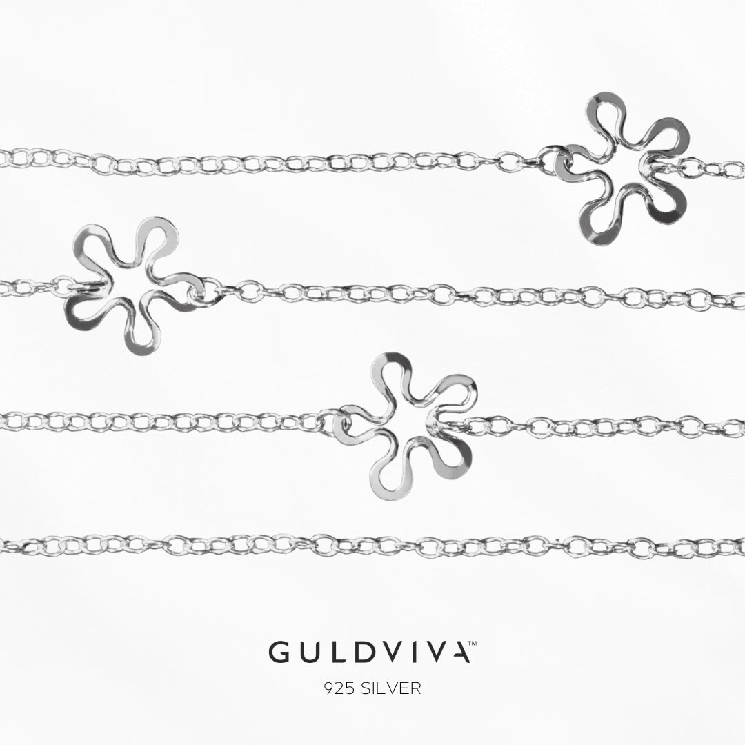 BLOMMAN kedja halsband i sterlingsilver med flera blomformade hängen längs kedjan mot vit bakgrund