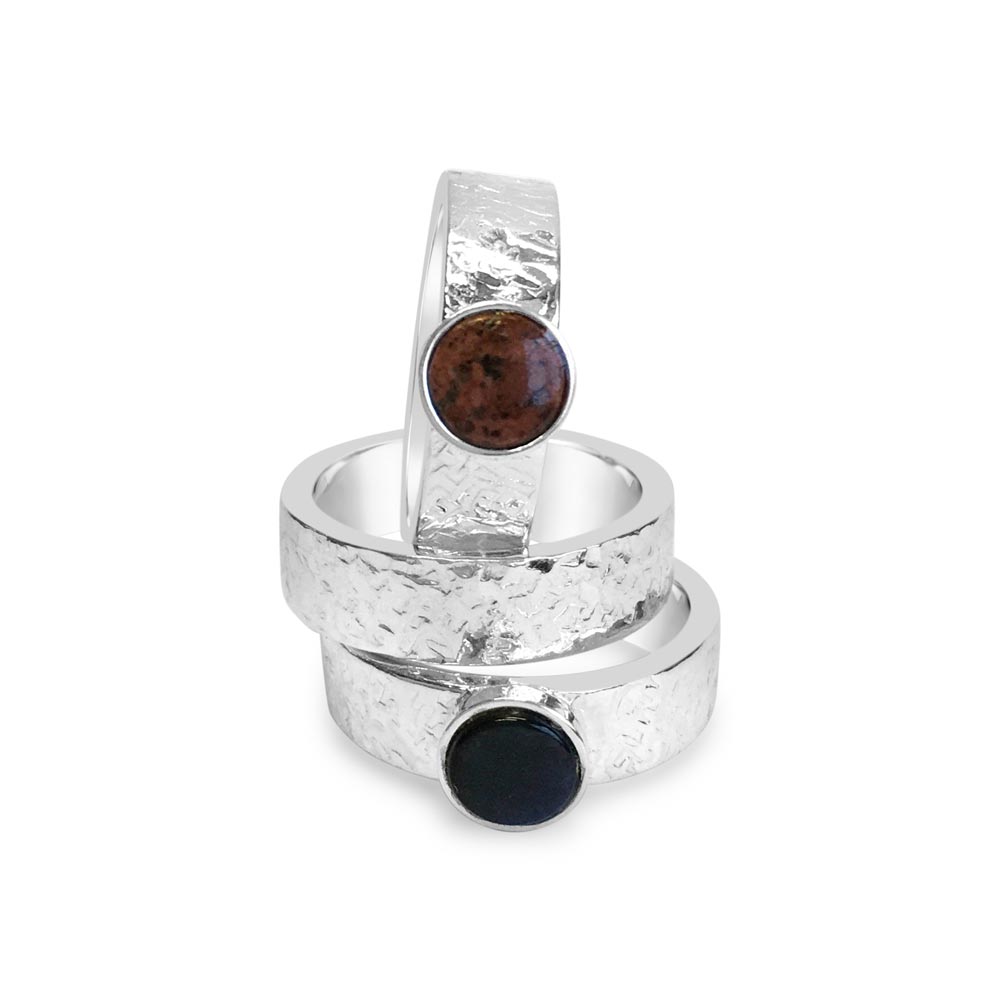 Three silver rings stacked together with hammered bands and round brown and navy stones