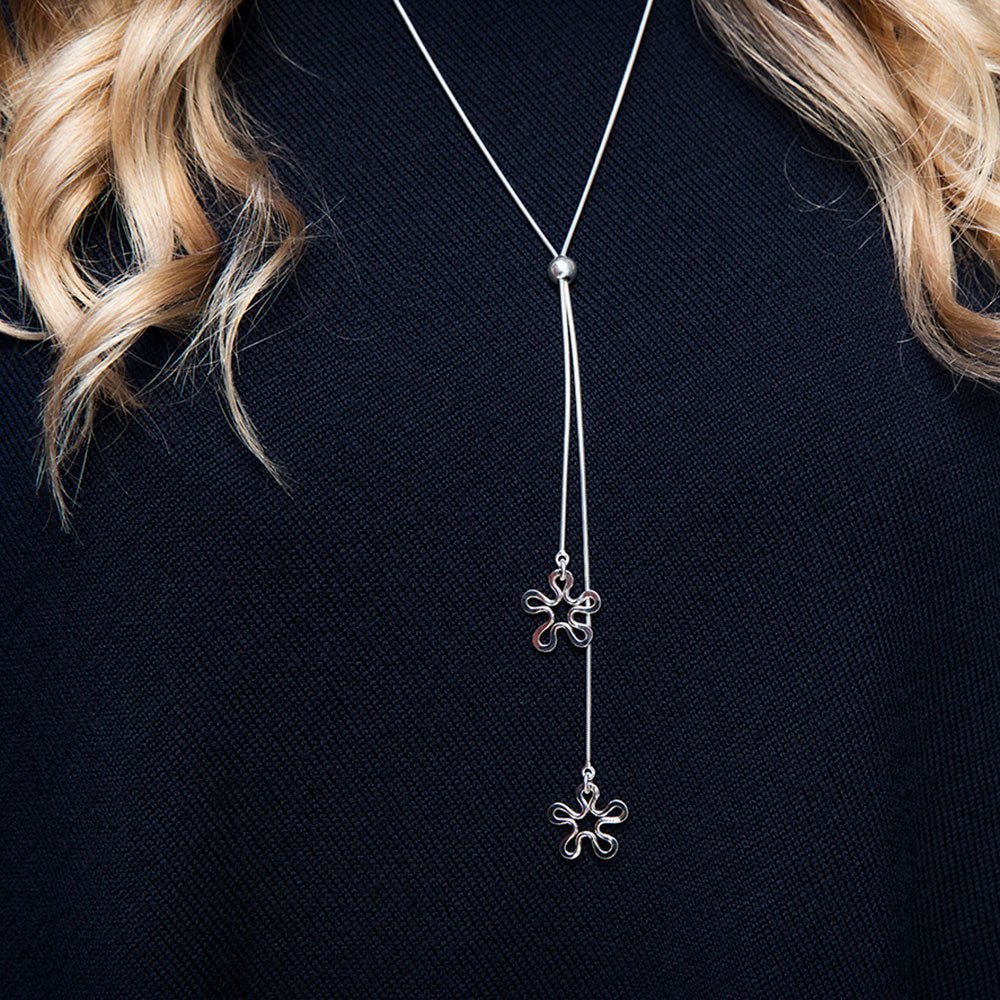 Silver BLOMMAN necklace with two flower pendants on separate strands worn over a dark sweater