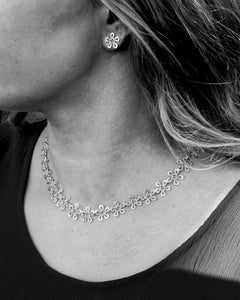 BLOMMAN collier exklusiv silver necklace with connected flower motifs worn on a model with a matching flower earring
