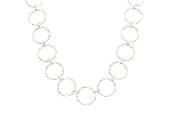 CIRCLA necklace in hammered circular links sterling silver laid flat against white background