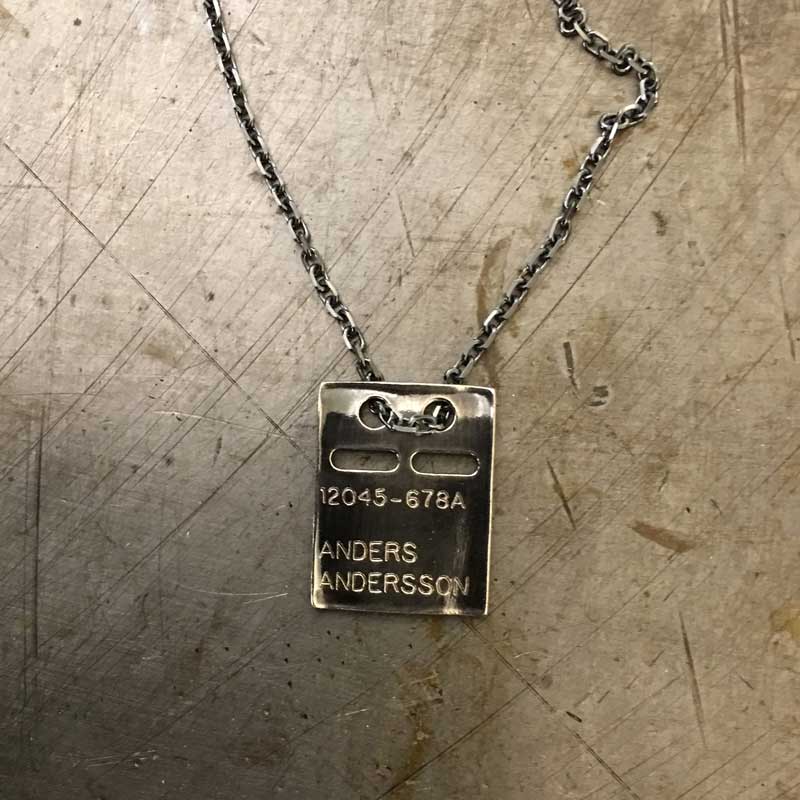 Silver rectangular pendant on a chain with two small top holes.