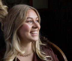 Smiling woman wearing BLOMMAN 18K collier exklusiv rose gold floral necklace.