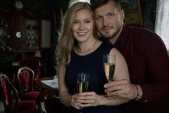 Couple posing with champagne; woman wears BLOMMAN 18K collier exklusiv floral necklace.