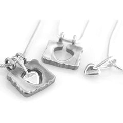 HÅLL OM MITT HJÄRTA halsband med grovt kantad kvadratram och ett hjärtsmycke i mitten på en ormkedja
