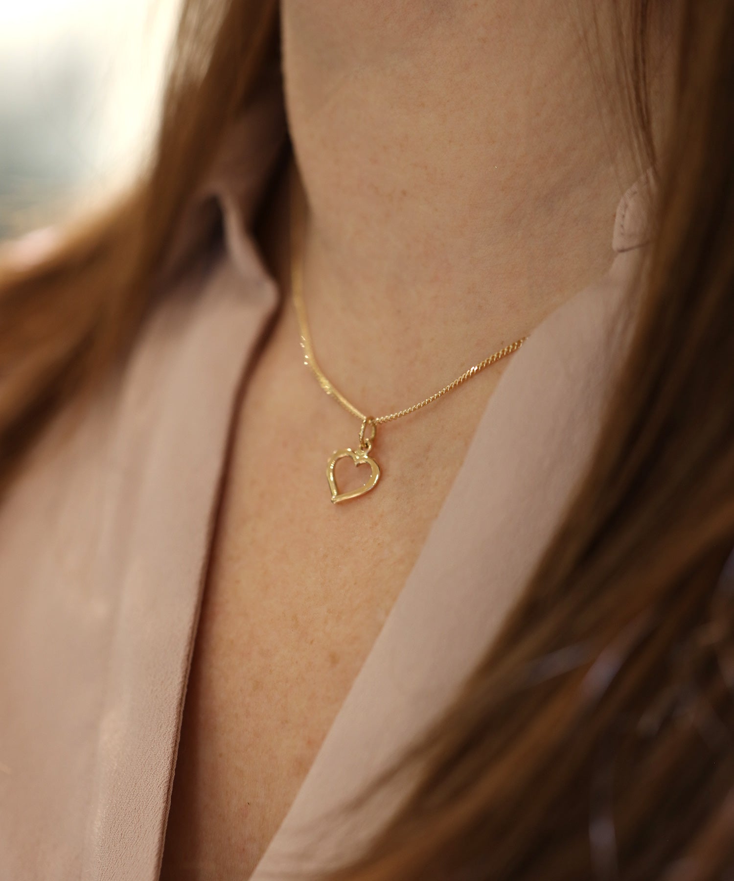 Öppet hjärta halsband i guld runt halsen på modell