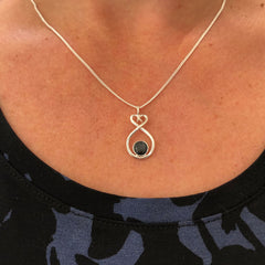 Silver halsband med oändlighetsslinga och två svarta stenar i ett dekorativt hänge