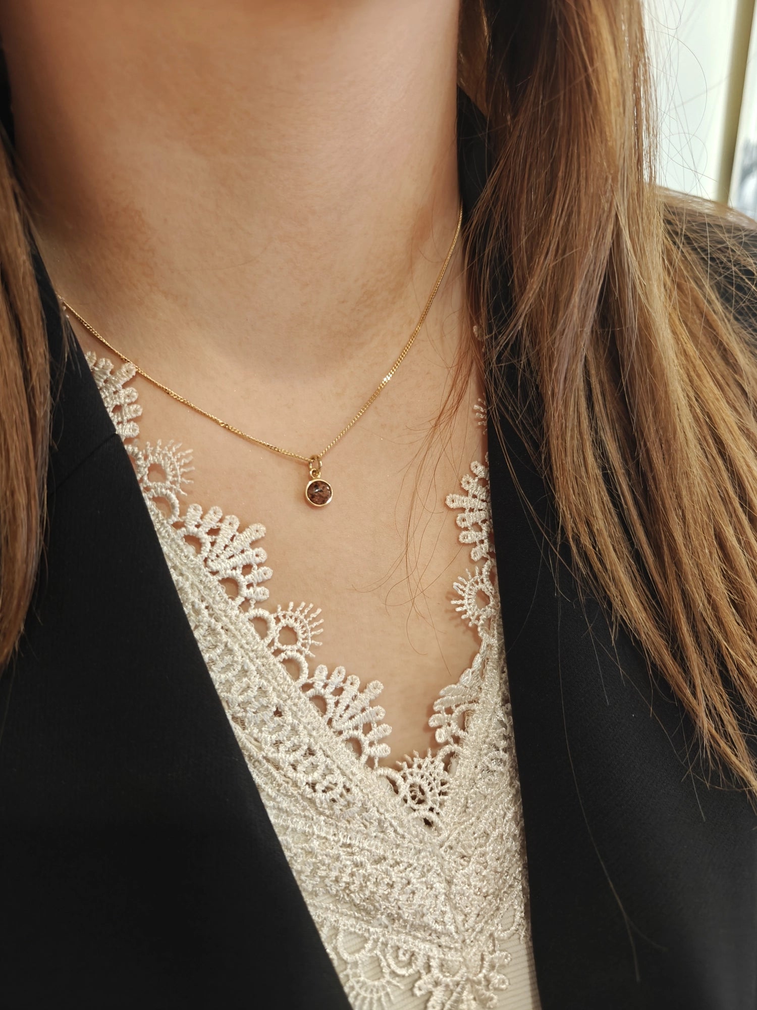 Basic Granit S 18K halsband med rund åländsk granit i guldfattning och tunn kedja mot vit bakgrund
