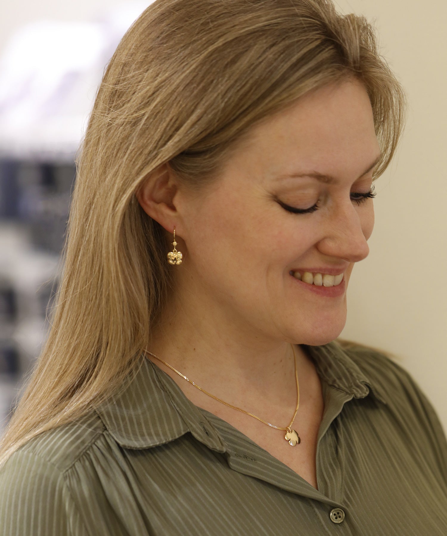 Kvinna bär guld Klöver örhängen på krok och matchande halsband