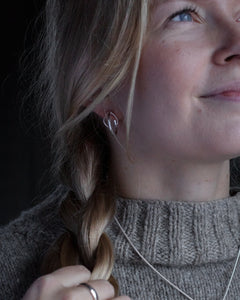 Kvinna bär STORMSKÄRS MAJA örhängen på stift i silver med öppen oval design