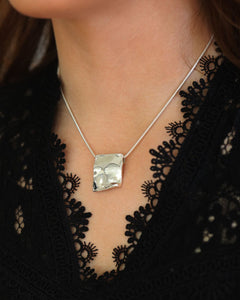 Close-up of PYRUS silver plate pendant on a snake chain at the neck
