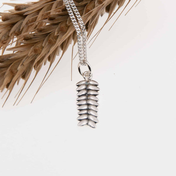 RÅG XS necklace with a silver pinecone pendant hanging from a chain.