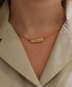 RÅG 18K halsband i guld med en böjd rad lövformade länkar över halsen.