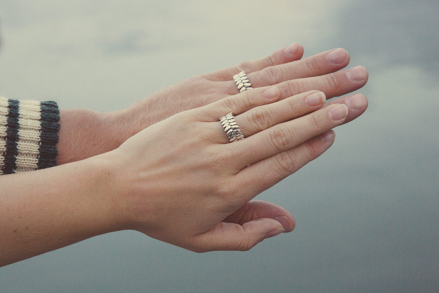 Close-up of hands wearing silver RÅG ROBUST rings.