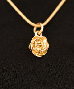 Närbild av rosformigt hänge på ROS 18K halsband med tunn kedja.