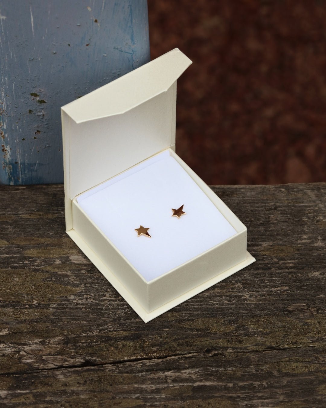 Pair of star shaped 18K gold stud earrings in an open white box