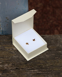 Pair of star shaped 18K gold stud earrings in an open white box