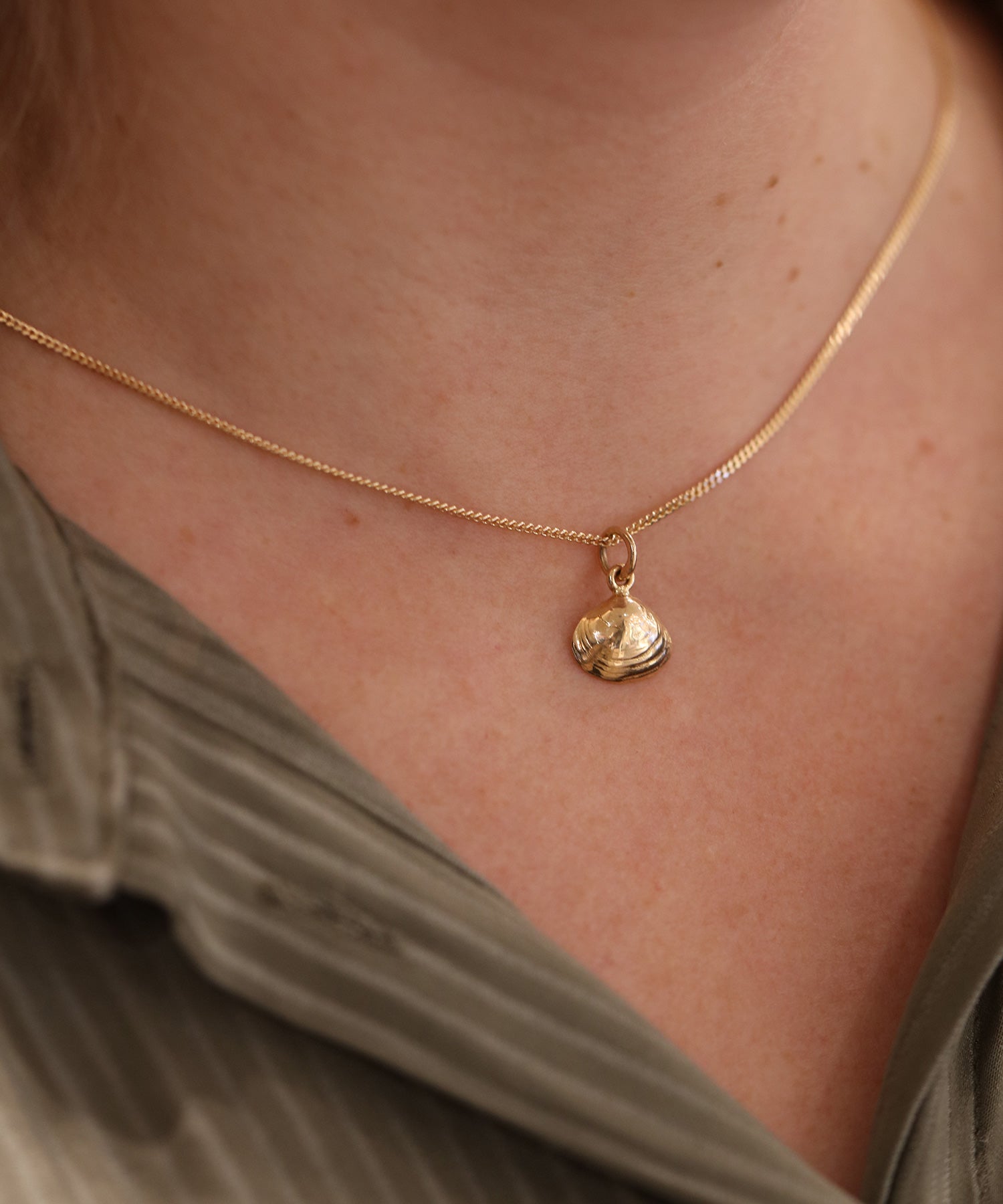 18K guld halsband med ett litet musslaformigt hänge på tunn kedja runt halsen