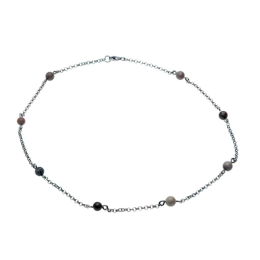 Armband med små färgade stenar längs en silverkedja liggande i cirkel på vit bakgrund