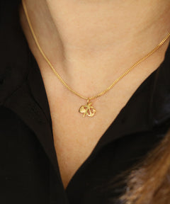 Person i svart topp bär Tro hopp och kärlek halsband i guld 18K XS runt halsen