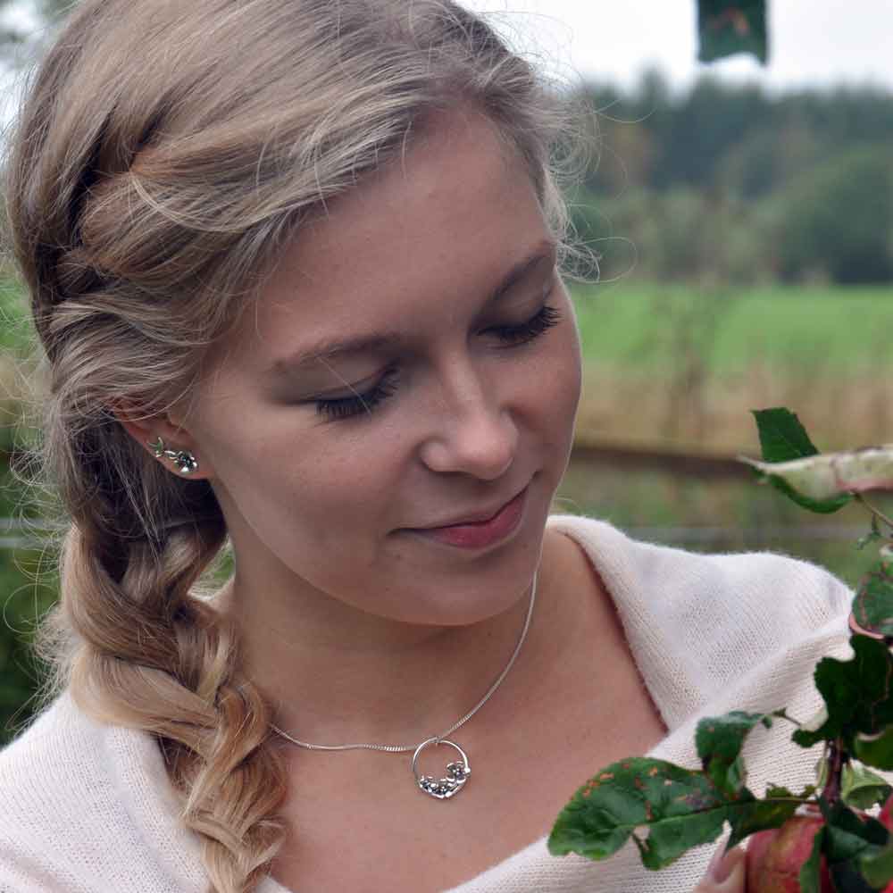 Närbild på kvinna som bär äppleblom stiftörhänge i örat