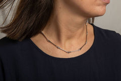 Peggy collier necklace in sterling silver with peg shaped links draped around a model's neck