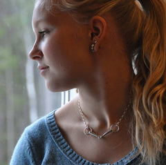 Side profile of a woman wearing BETSEL silver chain necklace and multiple small earrings
