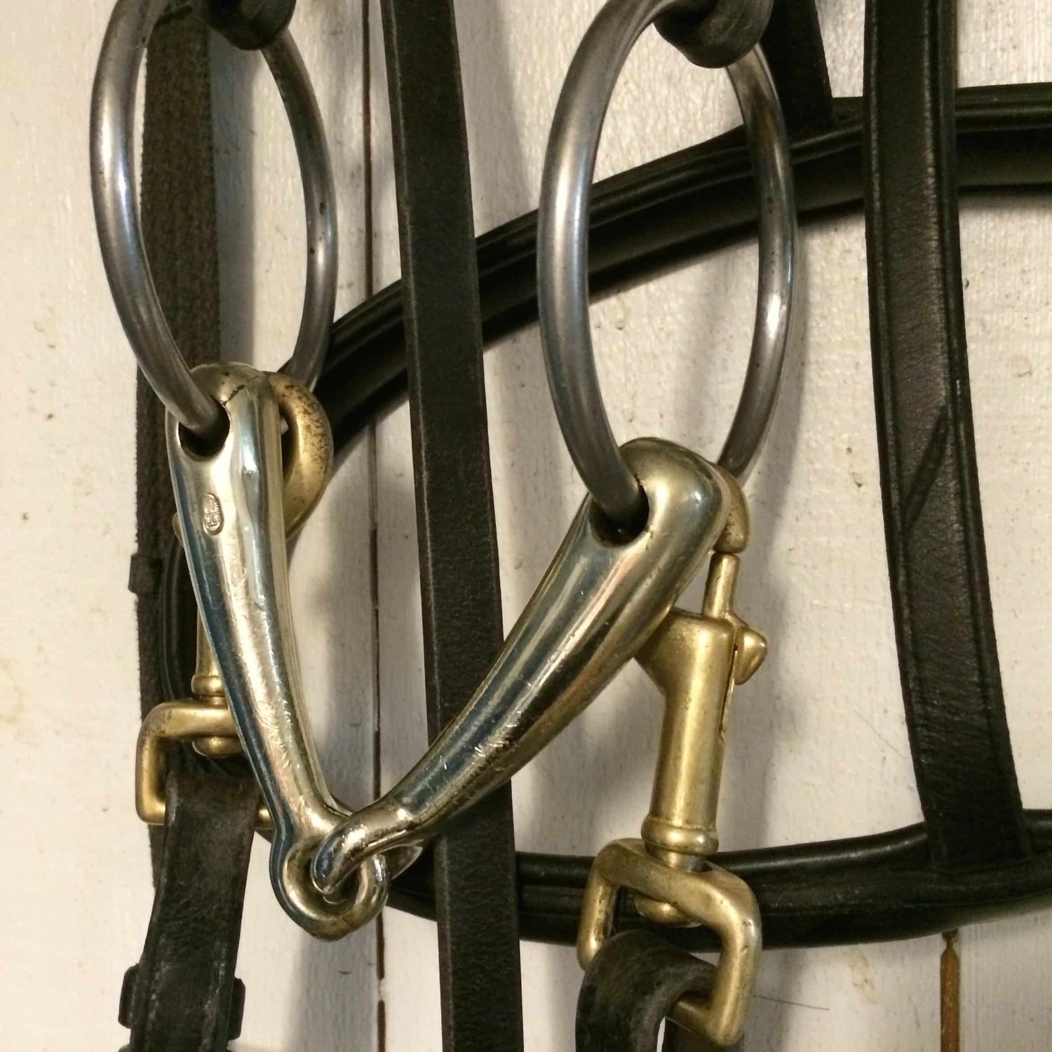 Closeup of several metal rings and leather straps hanging on a display rack