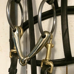 Closeup of several metal rings and leather straps hanging on a display rack