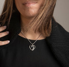 Kvinna bär ett sterlingsilvers halsband med öppet dubbelt hjärta