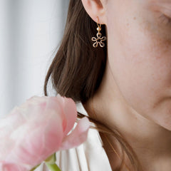 Närbild av öra med blomformade 18K guld örhängen på krok