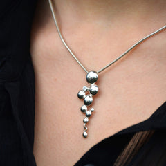Model wearing CELEBRATE halsband with a vertical cascade of silver bubbles