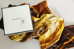Celebrate silk scarf in brown and gold tones displayed in an open gift box.