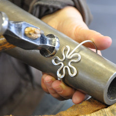 Jeweler shapes a BLOMMAN flower motif in sterling silver using a hammer during fabrication.