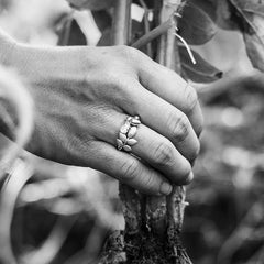 Close up of a hand wearing the EVA 18K ring with a leaf motif, gripping a plant root.