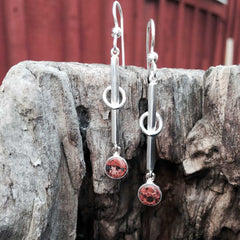 Gloria Granit örhängen på krok utomhus med vertikala stavar och röda granitcabochoner