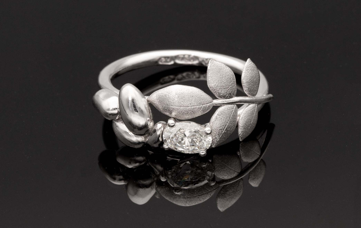 Close up of EVA 18K ring showing a large central diamond and leaf motif wrapping the shank