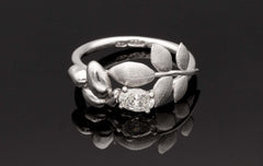 Close up of EVA 18K ring showing a large central diamond and leaf motif wrapping the shank