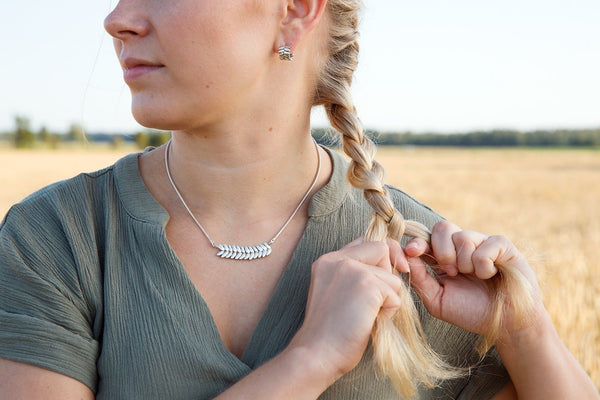 Silver RÅG L necklace worn by a woman outdoors with braided hair visible