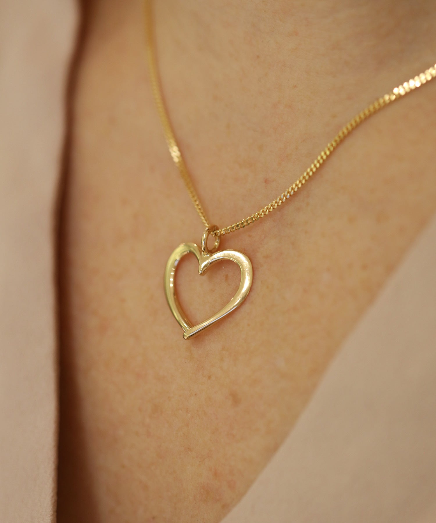 Närbild av öppet hjärtformat guldhänge på halsband